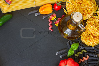 Raw pasta with ingridients on black board
