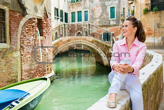 Woman sitting by canal in Venice