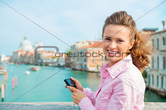 Smiling woman tourist holding camera above Grand Canal