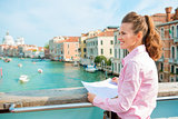 Smiling woman in profile holding map on bridge above Grand Canal