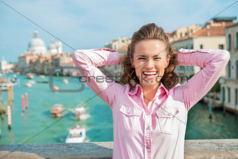 Laughing woman tourist with hands behind her head in Venice