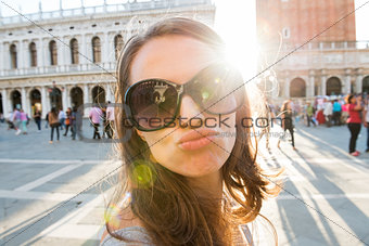 Woman tourist on St. Mark's Square taking selfie blowing a kiss