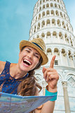 Happy woman tourist holding map and pointing at Tower of Pisa