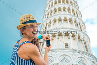 Smiling woman tourist taking photo of Leaning Tower of Pisa