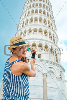 Happy female tourist taking photo of Leaning Tower of Pisa