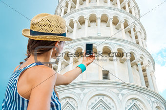 Woman seen from behind taking photo of Leaning Tower of Pisa