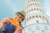 Closeup of woman holding and biting slice of pizza in Pisa