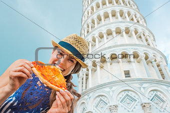 Closeup of woman holding and biting slice of pizza in Pisa