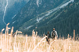 A couple walking in a meadow in front of a mountainous landscape