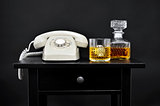 a retro telephone, a bottle and a glass with liquor on a table, 