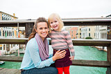 Happy mother kneeling down next to happy daughter in Venice