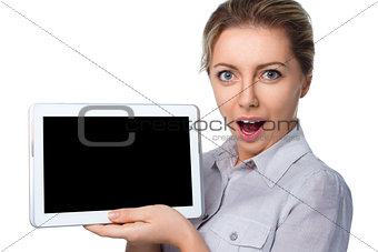 Young cheerful surprised woman is showing blank tablet 