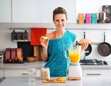 Happy, fit woman in the kitchen preparing a healthy smoothie