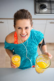 Athletic smiling woman holding freshly-made smoothie in kitchen