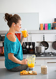 Woman in workout gear on kitchen counter drinking smoothie