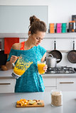Woman in workout gear pouring smoothie in kitchen
