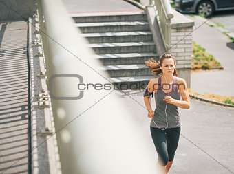 Woman jogger in the zone running along sidewalk