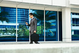 Businessman Reading Email On Mobile Phone Walking To Office