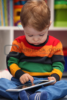 Happy 2 years old boy using a digital tablet computer