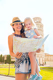 Mother holding daughter looking at map in Pisa in summer