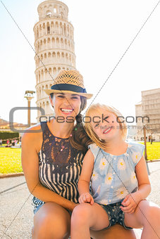 Happy mother kneeling with daughter sitting on her lap in Pisa