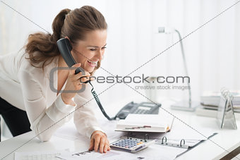 Happy businesswoman on telephone looking at document