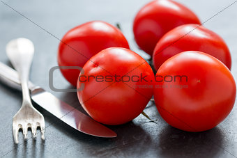 Ripe tomatoes, knife and fork.