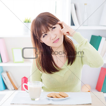 Asian girl thinking while having breakfast