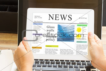 hands holding tablet with news site