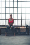 Fit woman sitting on bench in loft gym listening to music