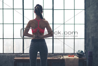 Rear view of woman with hands clasped behind back in yoga pose