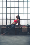 Fit, muscular woman relaxing on bench in loft gym with earbuds