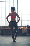Rear view of woman in workout gear standing with hands on hips