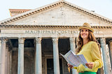 Happy woman standing by the Pantheon holding map in Rome