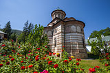Cozia monastery church with red flowers on a sunny summer day