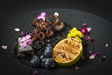 Risotto with octopus and blueberries on a black plate