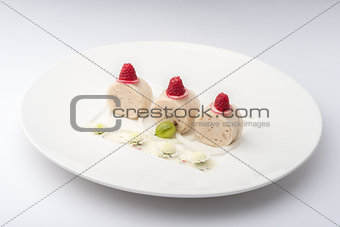 banana rolls with raspberries on a white plate on a white backgr