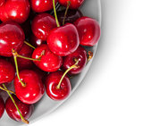 Closeup red sweet cherries in white plate top view