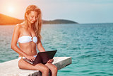 Woman sitting and relaxing on a beach with a laptop