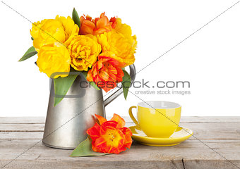 Colorful tulips bouquet in watering can and coffee cup