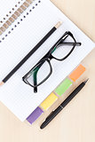 Office table with glasses, blank notepad and pencil