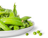 Closeup pile of green peas in pods in white plate