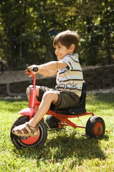 Boy riding tricycle.
