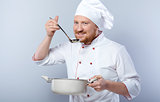 Head-cook tasting food from saucepan