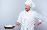 Head-cook holding pan and looking at camera
