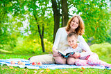 Mom and daughter in the park reading a book