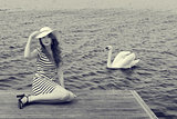 BW image of romantic girl near a swan on lake