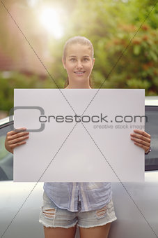 Woman Holding Empty White Board in front of her Car