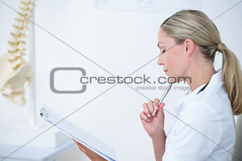 Doctor writing on clipboard at her desk