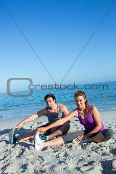 Happy couple stretching together beside the water
